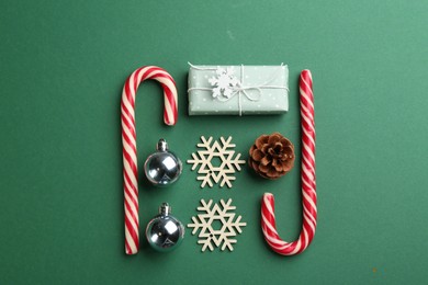 Photo of Flat lay composition with candy canes and Christmas decor on green background