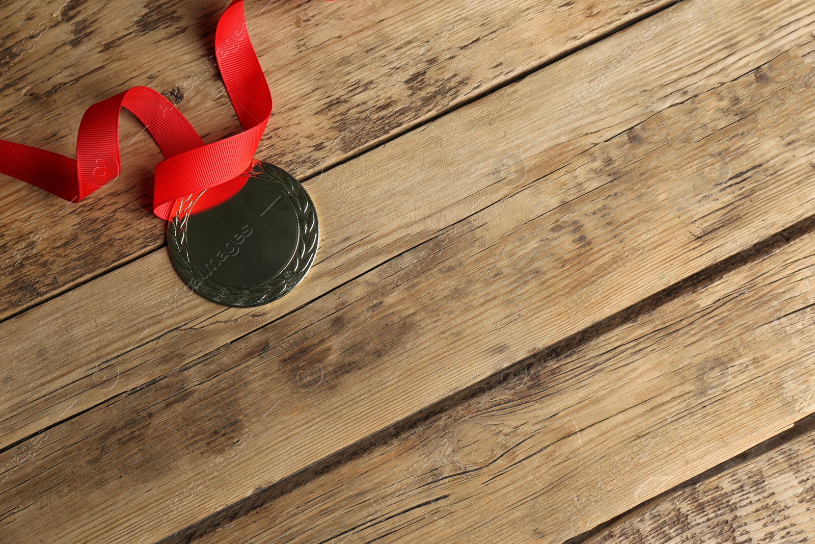 Photo of Medal with red ribbon on wooden background, top view. Space for design