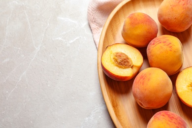 Plate with delicious ripe peaches on grey background, top view