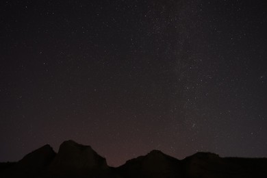 Photo of Picturesque view of starry sky at night over hill