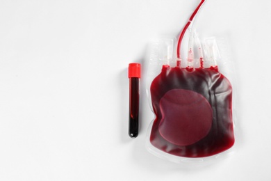 Photo of Blood pack for transfusion and test tube on white background, top view. Donation day