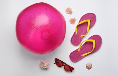 Photo of Beach ball, sunglasses and flip flops on white background, flat lay