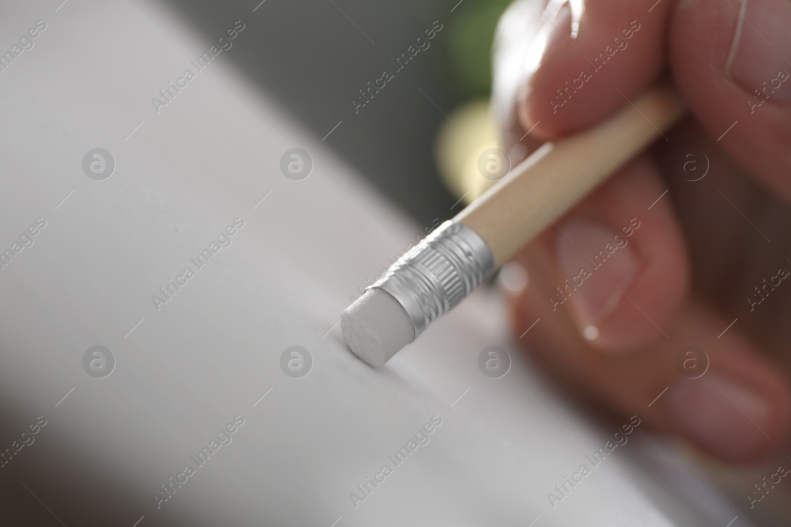 Photo of Man correcting picture on paper with pencil eraser, closeup