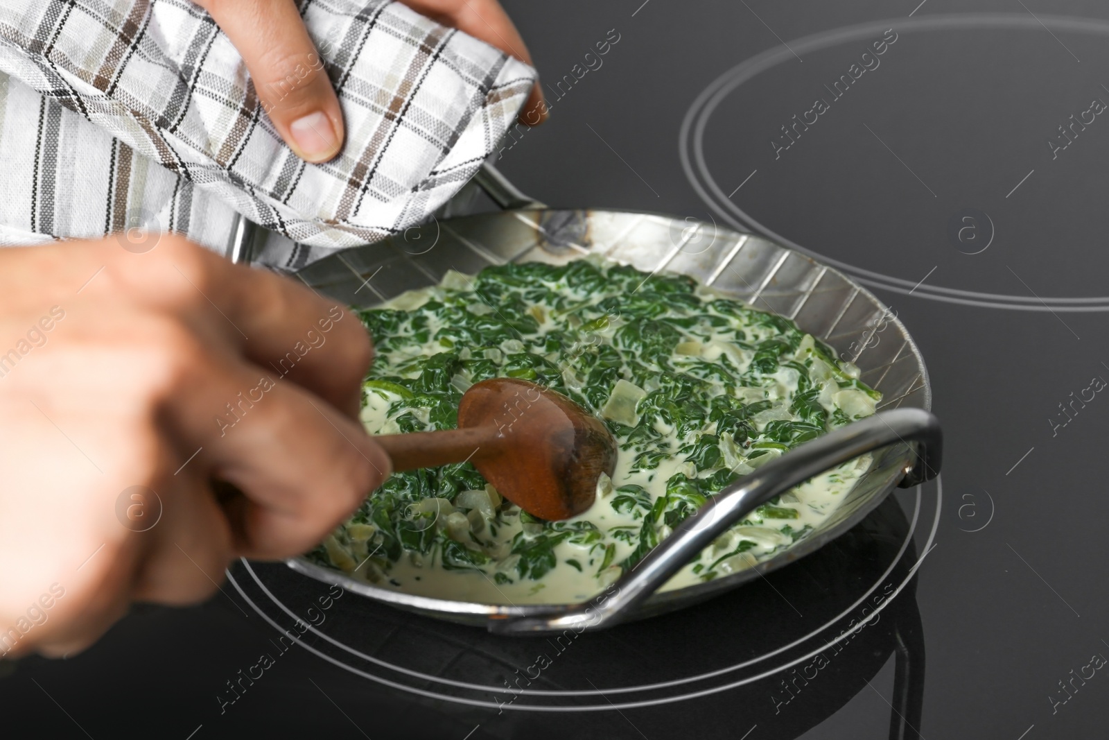 Photo of Woman cooking tasty spinach dip on kitchen stove, closeup view