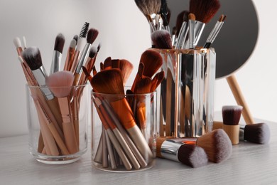 Photo of Set of professional brushes and mirror on wooden table