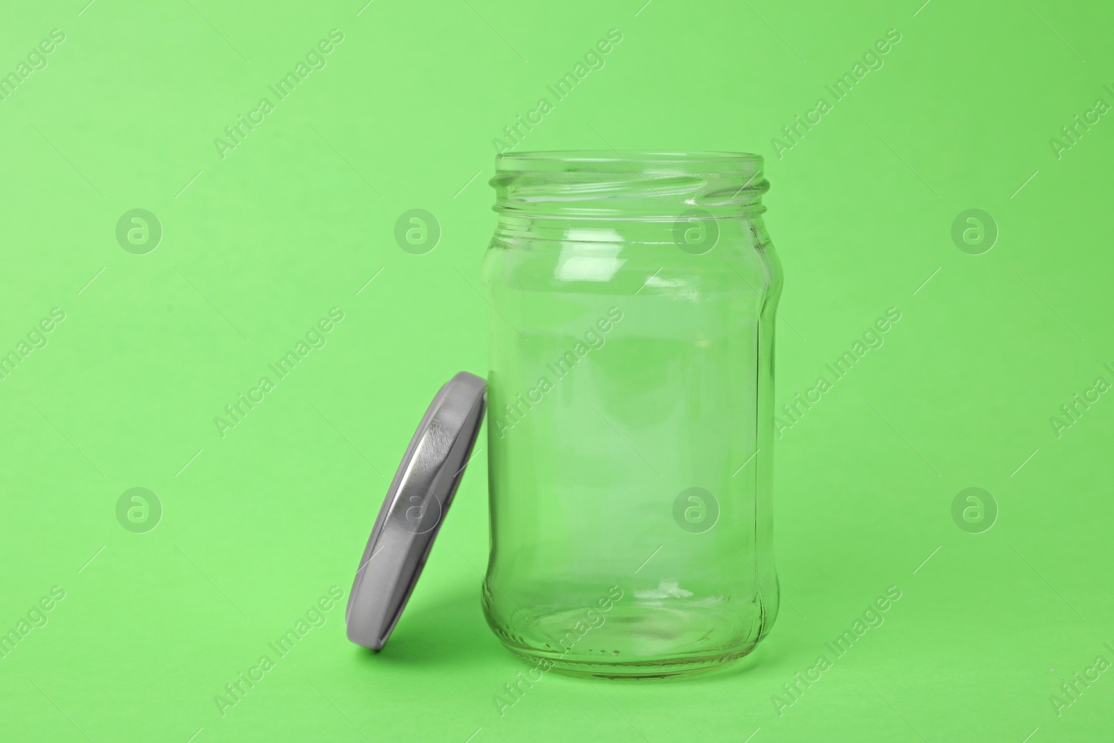 Photo of Open empty glass jar on light green background