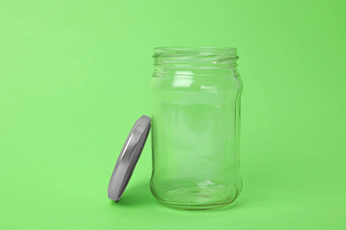 Photo of Open empty glass jar on light green background