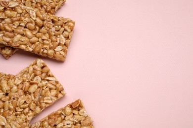 Photo of Tasty peanut bars (kozinaki) on pink background, flat lay. Space for text