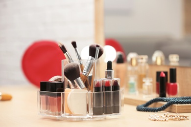 Photo of Organizer with cosmetic products and makeup accessories on dressing table