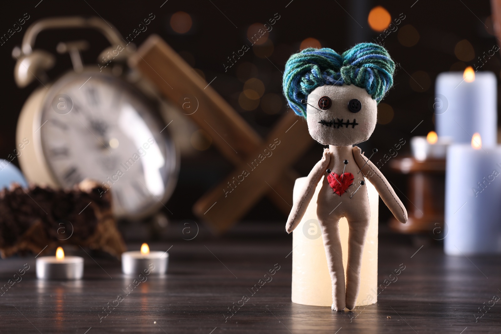 Photo of Female voodoo doll with pins in heart and ceremonial items on wooden table, space for text