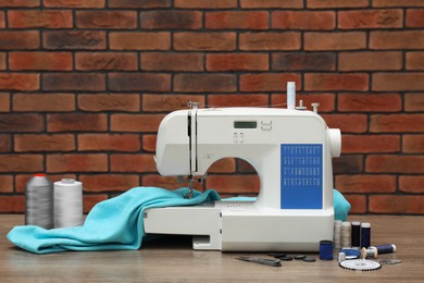 Photo of Sewing machine with fabric and craft accessories on wooden table against brick wall