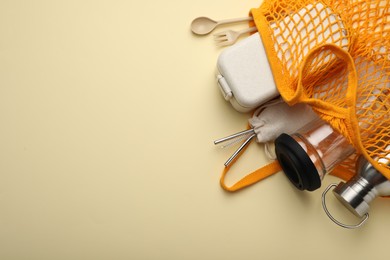 Mesh bag with eco friendly products on beige background, top view and space for text. Conscious consumption