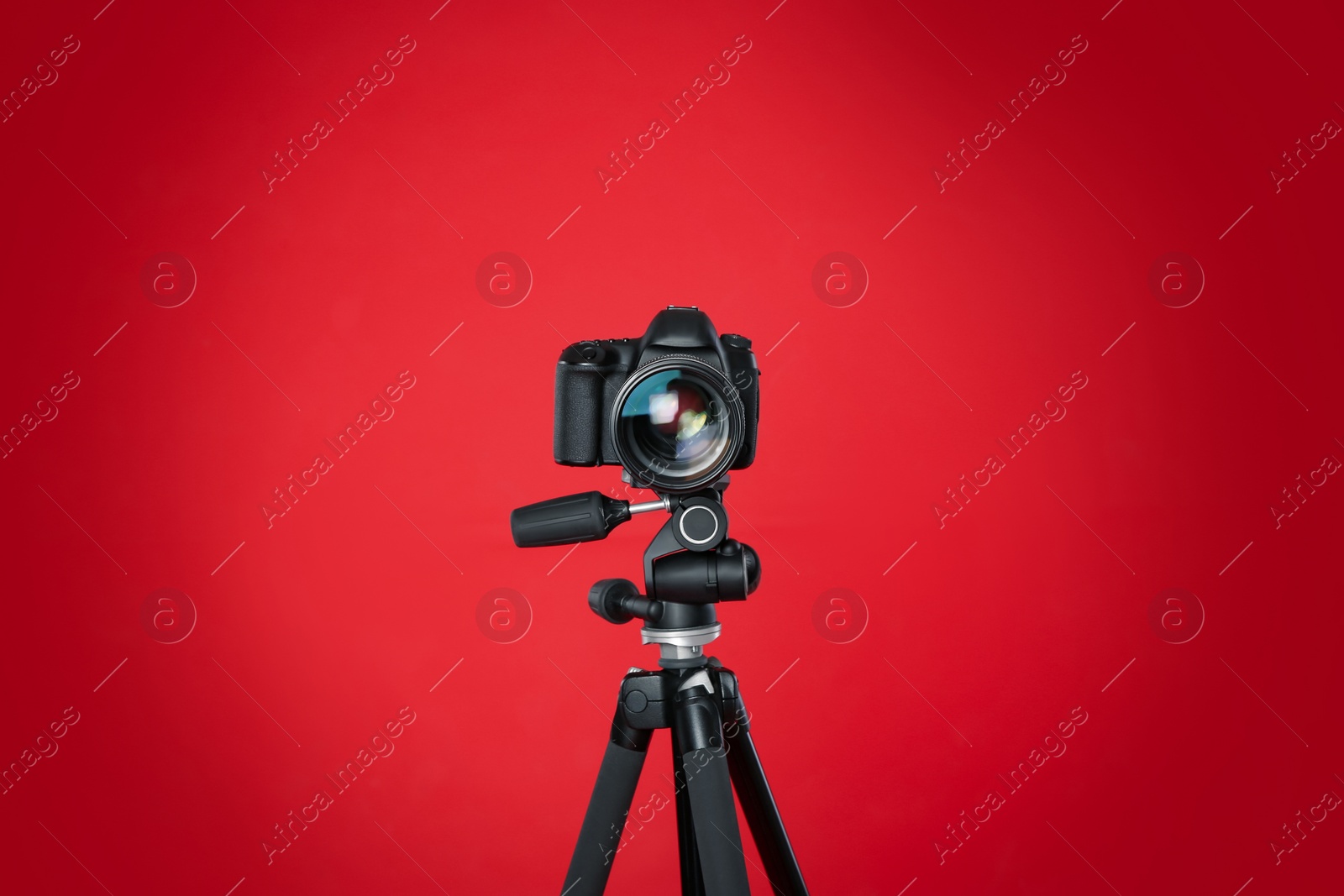 Photo of Modern professional video camera on red background