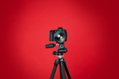 Photo of Modern professional video camera on red background