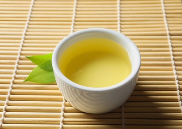 Photo of Cup of freshly brewed oolong tea on bamboo mat