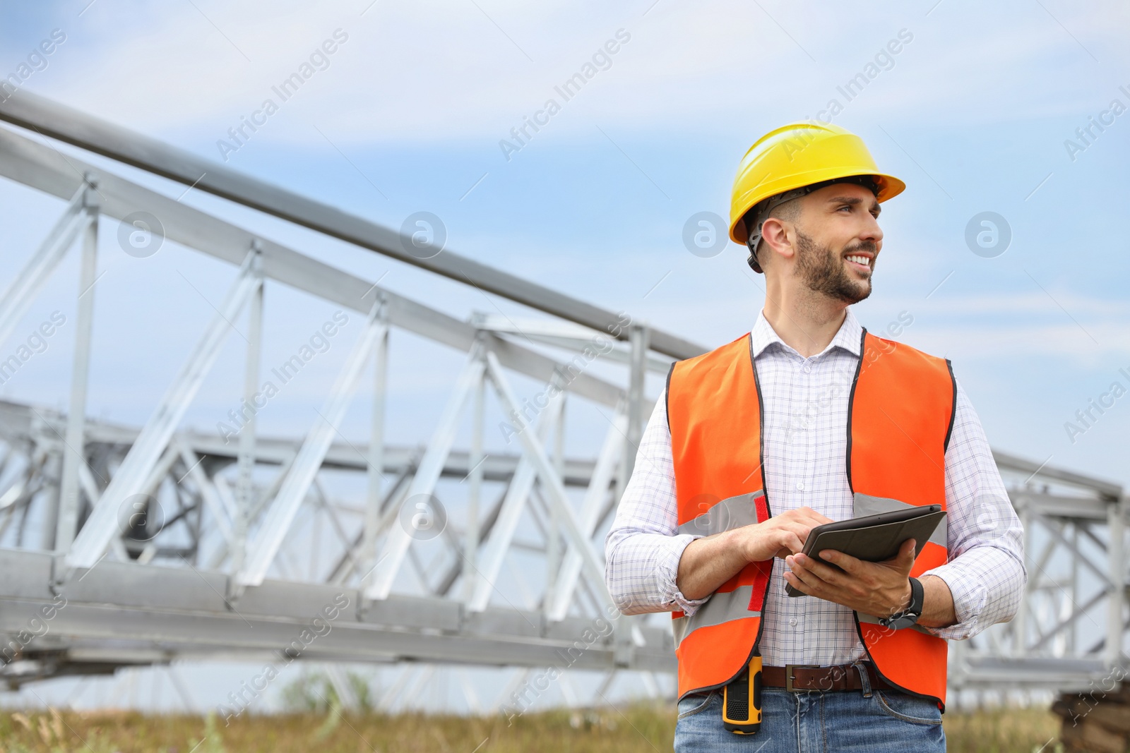 Photo of Professional engineer with tablet near high voltage tower construction outdoors. Installation of electrical substation