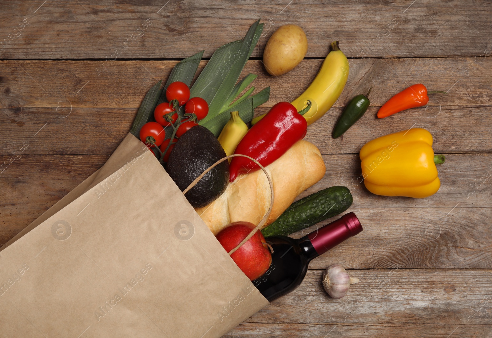 Photo of Shopping paper bag with different groceries on wooden background, flat lay