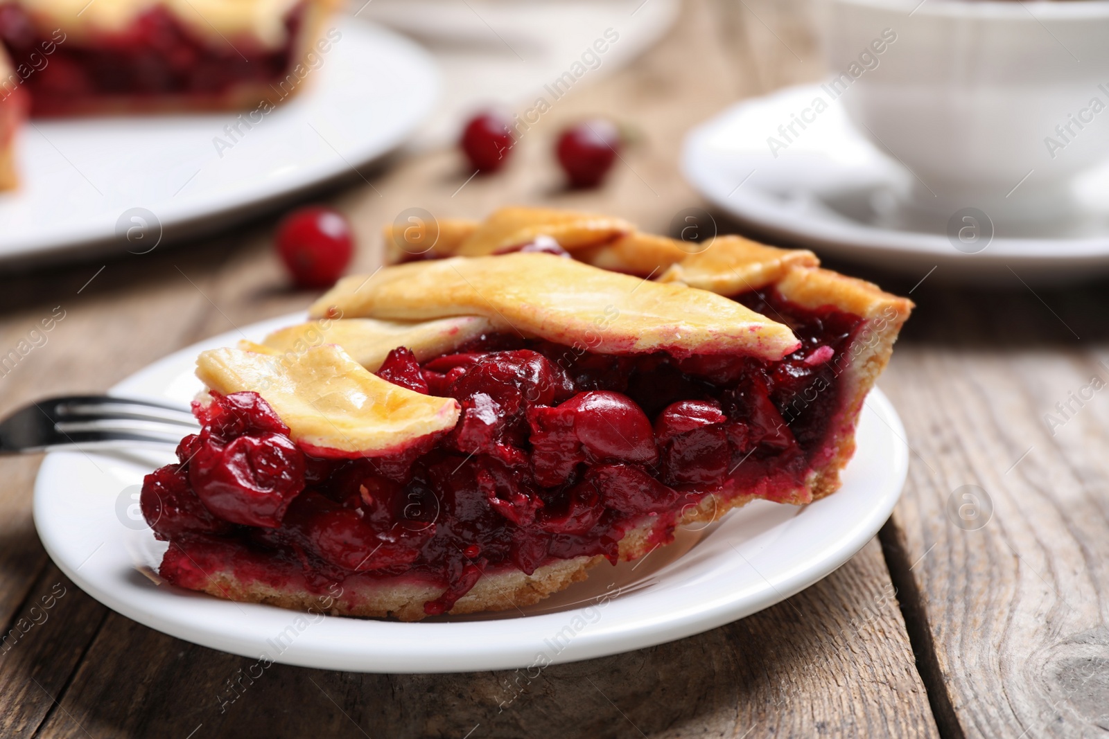 Photo of Slice of delicious fresh cherry pie on wooden table, closeup