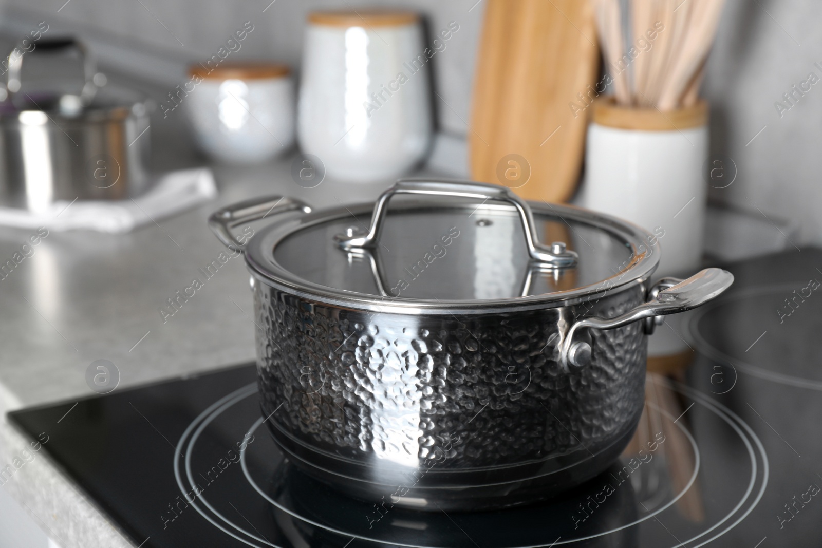 Photo of Pot with lid on cooktop in kitchen. Cooking utensil