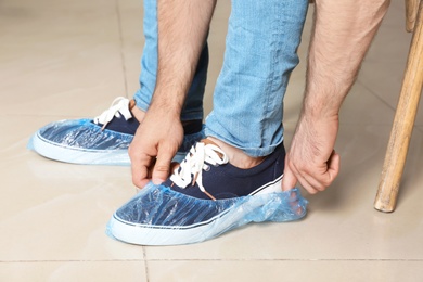 Man putting on blue shoe covers, closeup