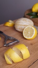 Photo of Lemon zest. Rind, fresh fruits and peeler on wooden table