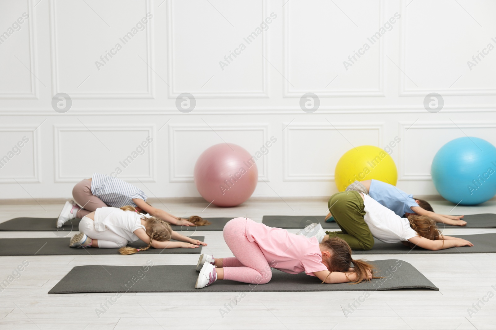 Photo of Group of children doing gymnastic exercises on mats indoors