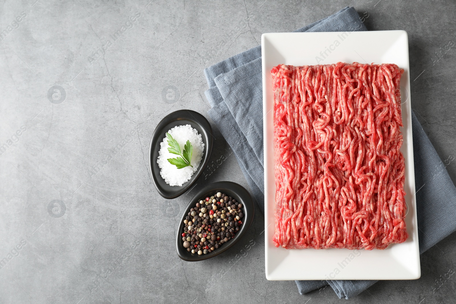 Photo of Raw ground meat and spices on grey table, top view. Space for text