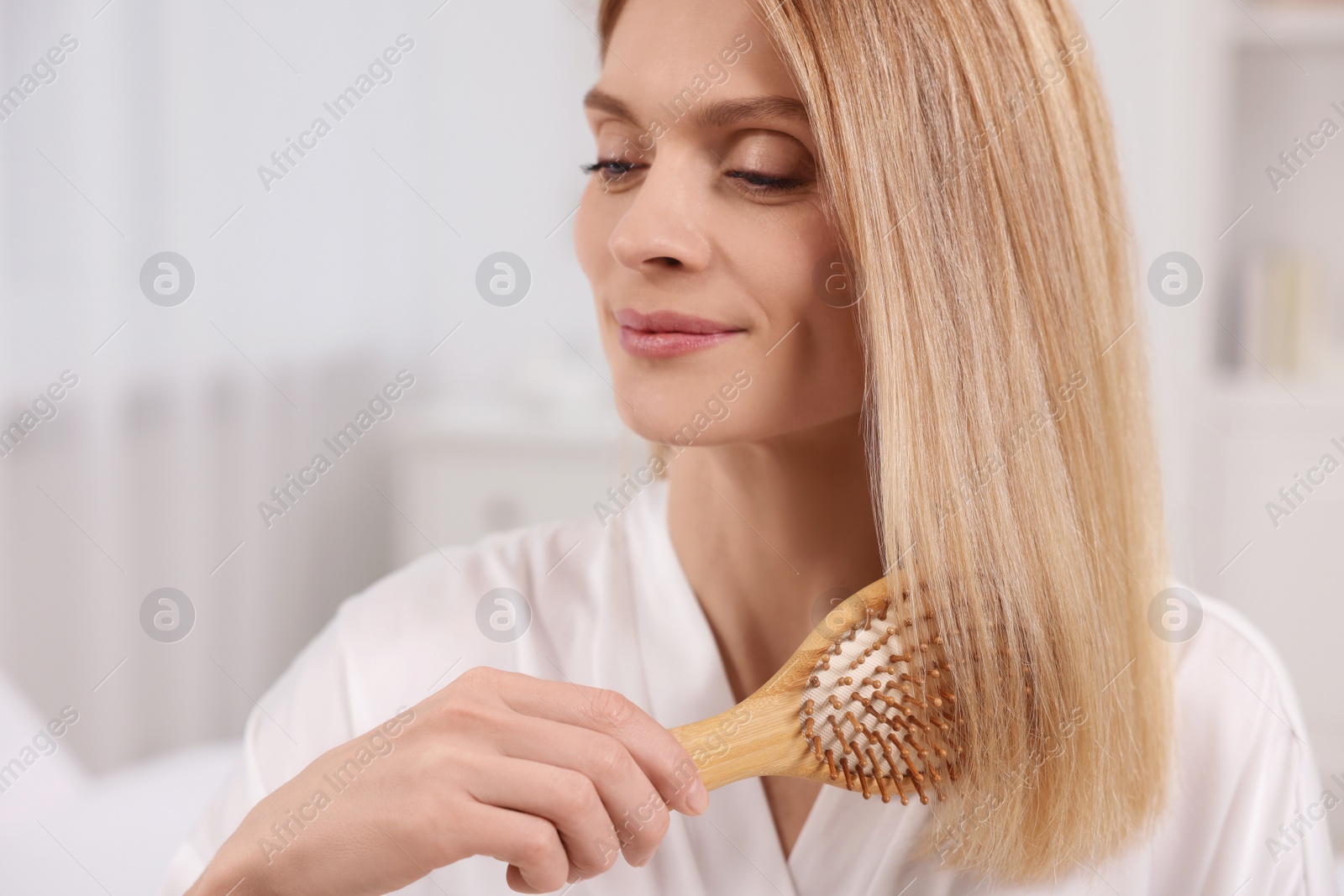 Photo of Beautiful woman brushing her hair in room