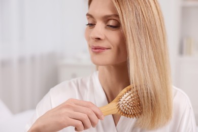 Beautiful woman brushing her hair in room