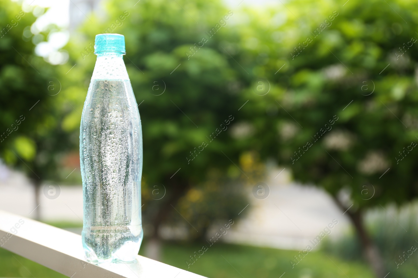Photo of Plastic bottle of cold pure water outdoors. Space for text