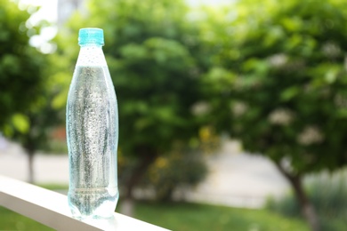 Plastic bottle of cold pure water outdoors. Space for text
