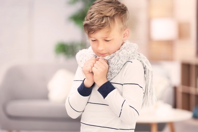 Photo of Sad little boy suffering from cold on blurred background