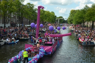 Photo of AMSTERDAM, NETHERLANDS - AUGUST 06, 2022: Many people in boats at LGBT pride parade on river