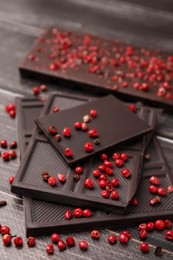 Delicious chocolate and red peppercorns on wooden table, closeup