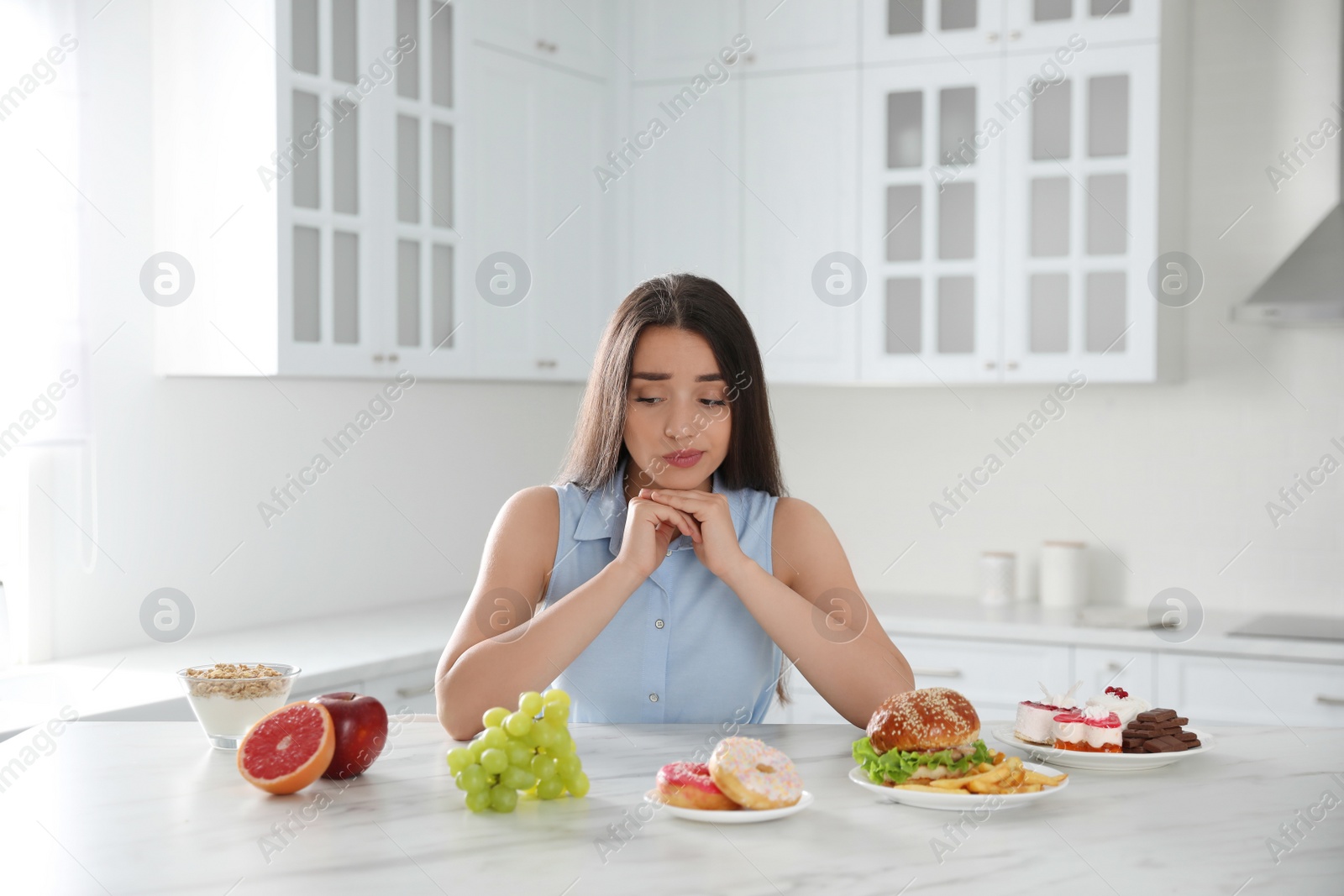 Photo of Concept of choice between healthy and junk food. Woman with products in kitchen