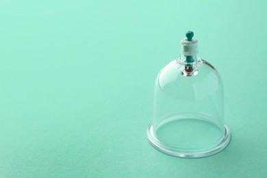 Photo of Plastic cup on turquoise background, space for text. Cupping therapy