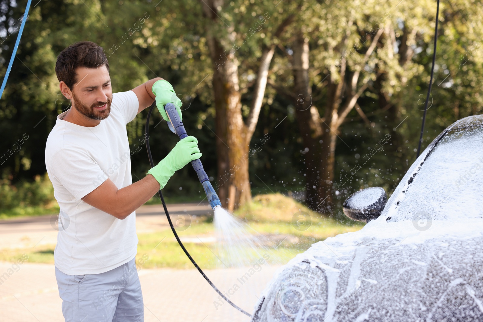 Photo of Man covering automobile with foam at outdoor car wash