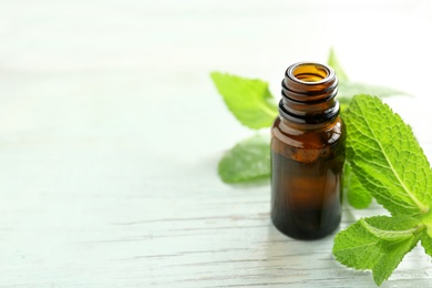 Bottle of essential oil and mint leaves  on wooden table