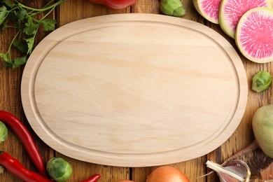 Photo of Empty cutting board and different vegetables on wooden table, flat lay. Space for text