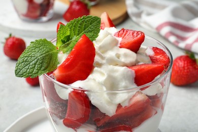 Photo of Delicious strawberries with whipped cream served on table, closeup