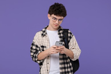 Portrait of student with backpack and smartphone on purple background