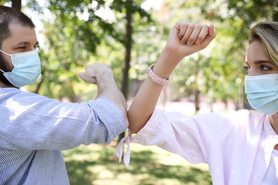 Photo of Man and woman bumping elbows to say hello outdoors, closeup. Keeping social distance during coronavirus pandemic