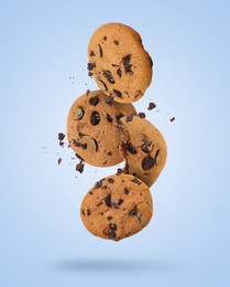 Image of Tasty chocolate chip cookies falling on light blue background