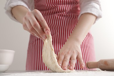 Woman with fresh dough at table, closeup. Cooking grissini