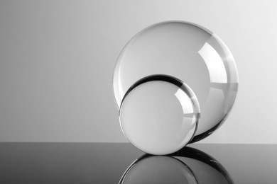 Photo of Transparent glass balls on mirror surface against light background