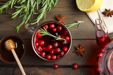 Photo of Tasty hot cranberry tea and fresh ingredients on wooden table, flat lay