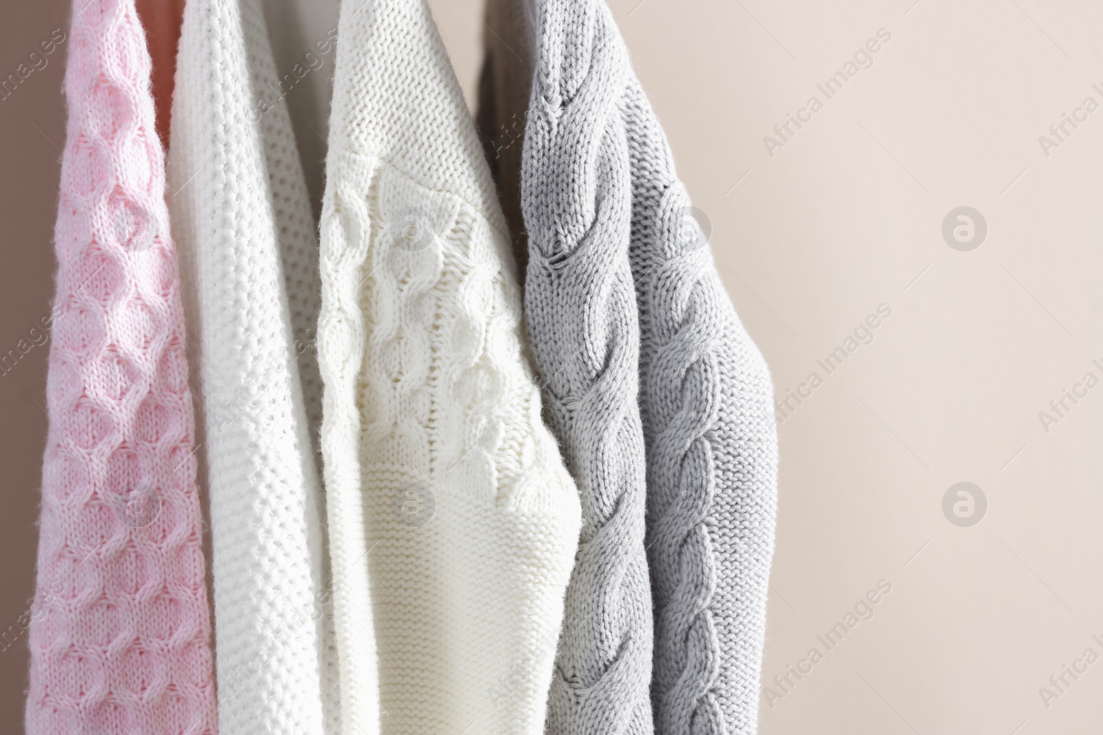 Photo of Collection of warm sweaters on light background, closeup