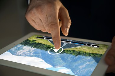 Image of Man touching tablet screen to play video, closeup