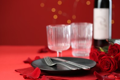 Place setting with roses for romantic dinner on red table, closeup. Space for text