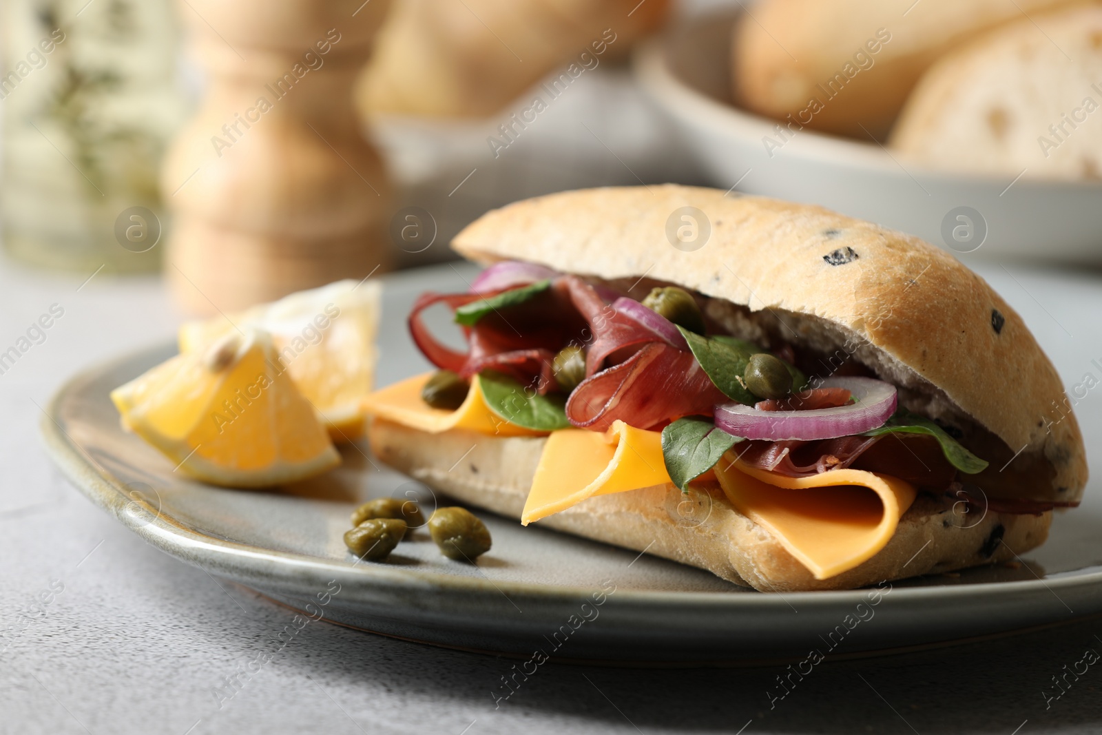 Photo of Delicious sandwich with bresaola, cheese and onion on light grey table, closeup